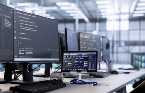 Computers in data center hosting rackmount ensuring faultless operations conditions. Close up of PC monitors and tablet on desk used for monitoring data center devices energy consumption