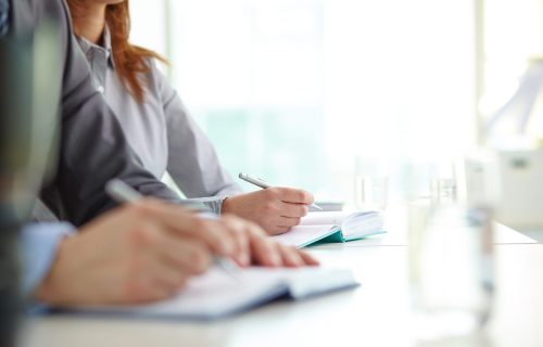 Hand of businesswoman with ballpoint over open notebook at convention